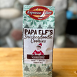 Load image into Gallery viewer, Box of Espresso Bay Papa Elf&#39;s Snickerdoodle Cookies on a wooden surface with a stone wall background
