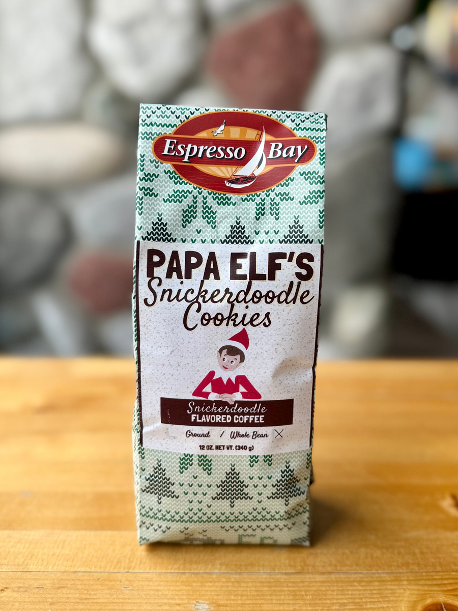 Box of Espresso Bay Papa Elf's Snickerdoodle Cookies on a wooden surface with a stone wall background